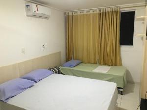 two beds in a hospital room with a window at Apartamento Beira Mar Manaíra in João Pessoa