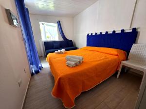 a bedroom with an orange bed with two towels on it at Elivulcano3 - PROPPRO SRL - isole eolie in Vulcano