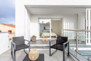 a balcony with two chairs and a bed in a bedroom at Aroeira Luxury Azul Villa, Lisboa, Beach, Surfing, Golf, Exploring, Hiking, Fishing in Charneca