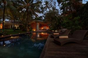 una piscina con sillas y una casa en Umah Tampih Luxury Private Villa - CHSE Certified, en Ubud