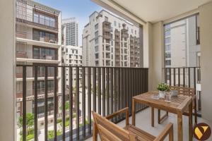 a balcony with a wooden table and a view of buildings at Vogue Rosewater Two Bedroom Apartment at Dubai Creek Harbour with Balcony and access to Pool, Gym, Kids Area and Near Shopping in Sabkhah