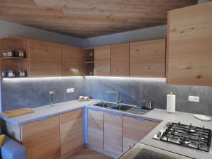 a kitchen with wooden cabinets and a sink at Arnika Hütte - un'immersione nelle montagne della foresta millenaria in Ugovizza