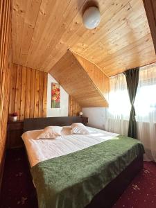 a bedroom with a large bed with a wooden ceiling at Vila Sofia in Predeal