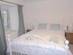 a bedroom with a white bed with blue pillows at Churchtown Cottage in Cubert +12 photos
