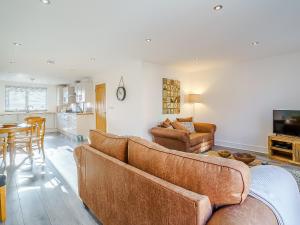 a living room with two brown couches and a kitchen at Seacote Gardens in St Bees