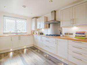 a kitchen with white cabinets and a wooden floor at Seacote Gardens in St Bees +16 photos