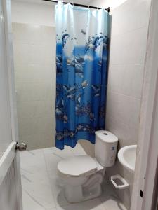 a bathroom with a toilet and a blue shower curtain at LA MEDELLIN HOSTAL in Cartagena de Indias