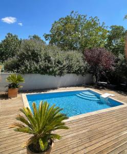 - une piscine dans une cour avec une terrasse en bois dans l'établissement La Tuilerie du Bazalac, à La Celle-sous-Gouzon
