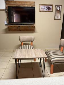 a table and a chair and a television on a wall at Casa Lalina in Laprida