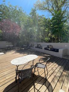 une table et deux chaises sur une terrasse en bois dans l'établissement La Tuilerie du Bazalac, à La Celle-sous-Gouzon
