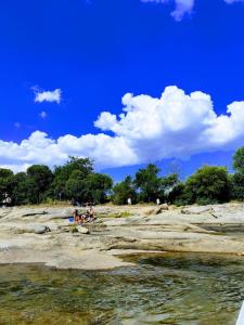 a group of people sitting on the rocks near the water at Hotel Alumine in Villa Cura Brochero
