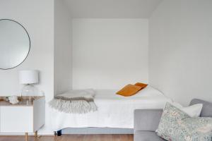 a white bedroom with a bed and a couch at SELF-SERVICE penthouse studio in the heart of Turku! in Turku
