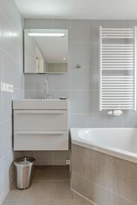 a bathroom with a sink and a tub and a mirror at De Noorderzon in Egmond aan Zee +33 photos