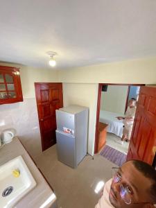a man sitting in a kitchen with a refrigerator at Paradise place small studio in Discovery Bay +5 photos