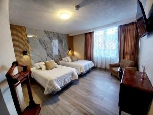 a hotel room with two beds and a desk at Royal Ruiz in Ibarra