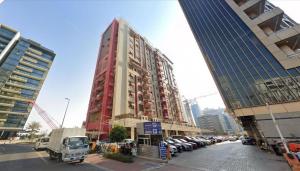 a tall red building with cars parked in a parking lot at delightful Partition Room Barsha Heights Tecom in Dubai