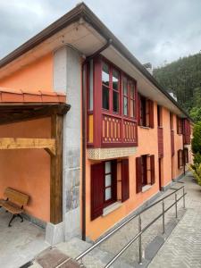 a building with red windows and a fence at La Casona Otañes HABITACIONES & APARTMENTS CASTRO URDIALES in Otañes