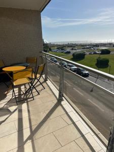 een balkon met een tafel en stoelen en uitzicht op een snelweg bij Le Grand Large Front de Mer in Le Touquet-Paris-Plage