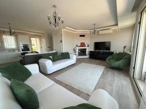 Una sala de estar con muebles blancos y una lámpara de araña. en Villa Panorama, en Cesme