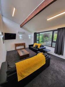 sala de estar con sofá negro y manta amarilla en Arcadian Motel, en Dunedin