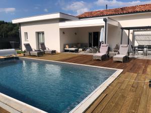 een huis met een zwembad en een houten terras bij Maison Landes in Mées
