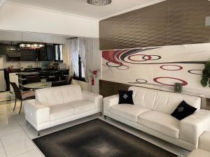 a living room with two white couches and a kitchen at Villa with private pool North coast in Dawwār Ḩalīs