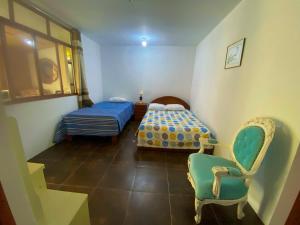a bedroom with two beds and a chair and a window at Casa Real - Oxapampa BnB in Oxapampa