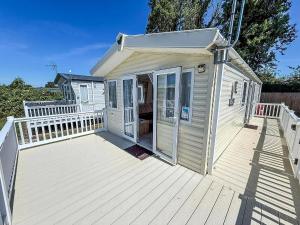 a small white house with a wooden deck at Gorgeous 6 Berth Caravan With Decking Area, Dovercourt Holiday Park Ref 44510A in Great Oakley