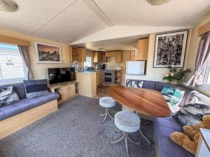 a living room with a couch and a table in a caravan at Great Caravan At Valley Farm Holiday Park, Essex Ref 46583V in Great Clacton