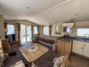 a living room with a couch and a table at Gorgeous 6 Berth Caravan With Decking Area, Dovercourt Holiday Park Ref 44510A in Great Oakley