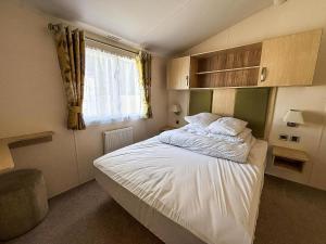 a bedroom with a bed with white sheets and a window at Gorgeous 6 Berth Caravan With Decking Area, Dovercourt Holiday Park Ref 44510A in Great Oakley +16 photos