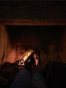 a person sitting in front of a fireplace at Casa de Campo Refúgio Jaguary in Monte Verde