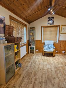 a living room with a chair and wooden floors at Readers Field Glamping in Great Sampford