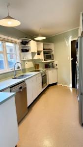 a large kitchen with white cabinets and a sink at Khandallah Home in Wellington