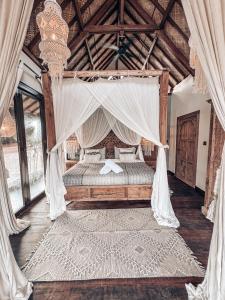 a bedroom with a canopy bed with curtains and a rug at Casa Magick boutique Villa in Gili Islands