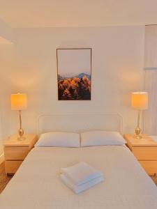 Un dormitorio con una cama blanca con dos lámparas. en Western Romaine, en Los Ángeles