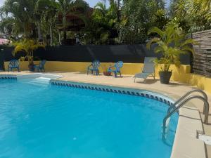 a swimming pool with blue chairs next to a resort at La citronnelle in Sainte-Anne