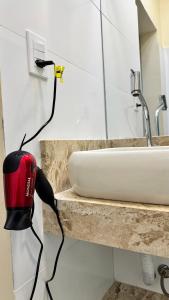 a blow dryer on a counter next to a sink at Studio 102 Pitangueiras no térreo - ar condicionado - na quadra da praia! in Guarujá
