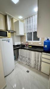 a kitchen with white cabinets and a white refrigerator at Studio 102 Pitangueiras no térreo - ar condicionado - na quadra da praia! in Guarujá
