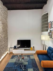 a living room with a tv and a blue couch at Aria B&B - apartment in the historic center in Spoleto