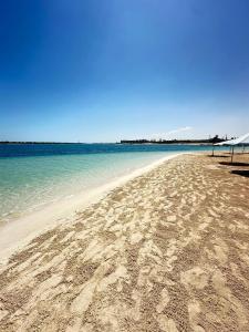 une plage de sable avec l'océan en arrière-plan dans l'établissement اصنع بعض الذكريات فيلا للإيجار مارينا الساحل الشمالي العلمين, à El Alamein