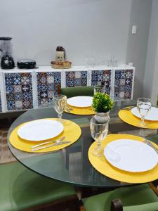 een eettafel met gele borden en glazen erop bij Casa ampla e confortável in Garanhuns