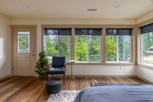 Un dormitorio con ventanas y una silla y un árbol de Navidad. en River Dance Cabin, en Packwood