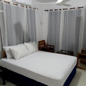 a bedroom with a bed with white sheets and curtains at Hotel Ningo in Santa Bárbara de Samaná