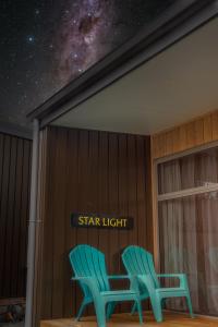 two green chairs in a room with a star light sign at Starlight Townhouse in Twizel