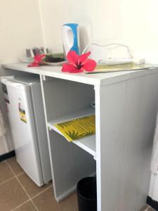 a white table with red flowers on it next to a refrigerator at Garden Reef Bungalows in Vitouara