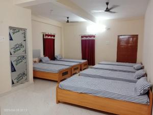 巴特那Hotel Vishwa Residency的带红色窗帘的客房内的三张床