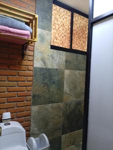 a bathroom with a toilet and a brick wall at "Arte en el desván" Rustic loft - Desván rústico in Tenancingo de Degollado +35 photos
