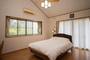 a bedroom with a bed and a large window at 南伊豆ガーデンヴィラ in Minamiizu