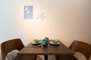 einen Holztisch mit zwei Tassen und Untertassen darauf in der Unterkunft Bellie Sangenjaya by Tranova in Tokio + 41 Fotos